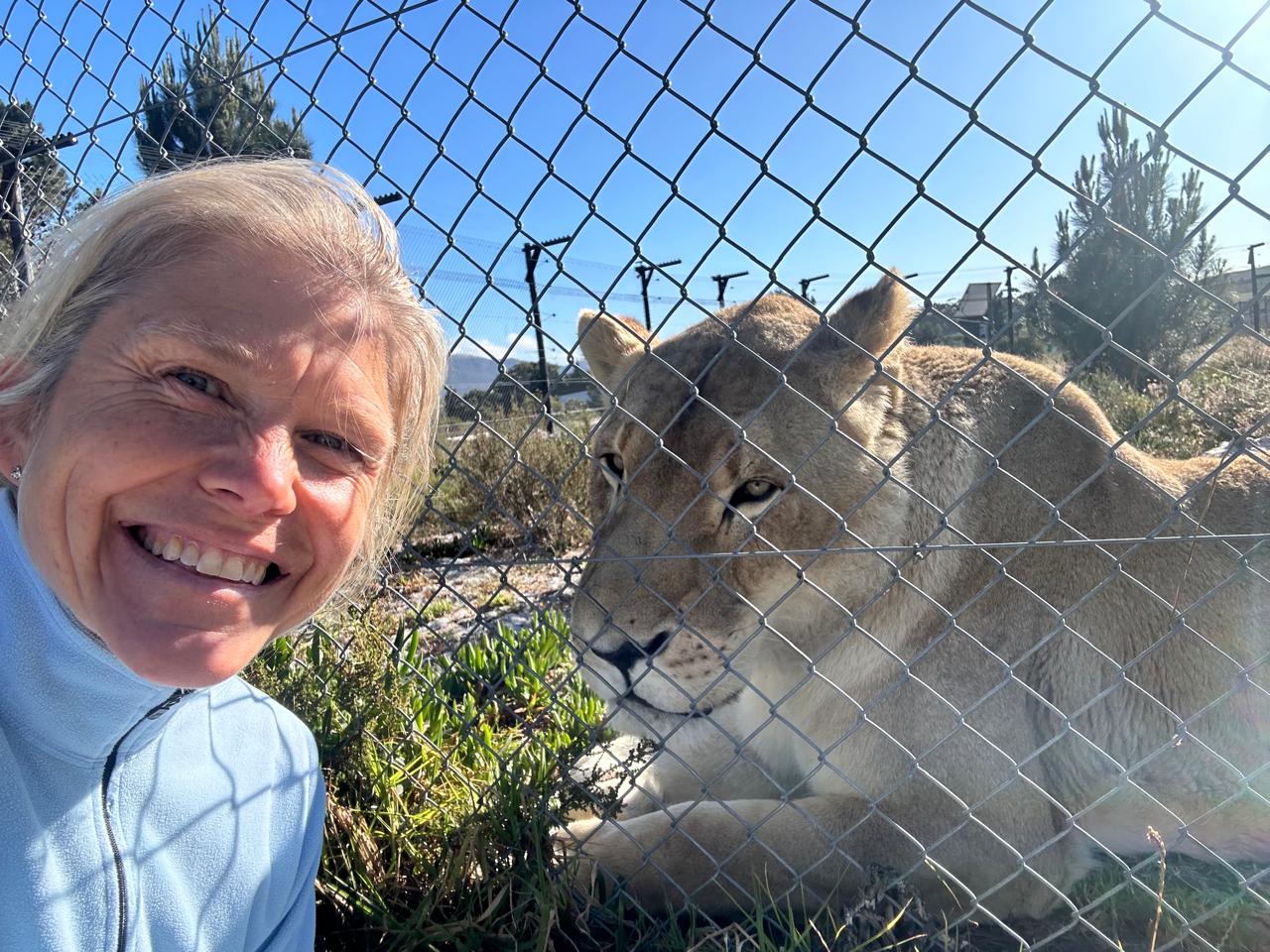 Cathrine and a lioness together at the fence line, both facing the camera